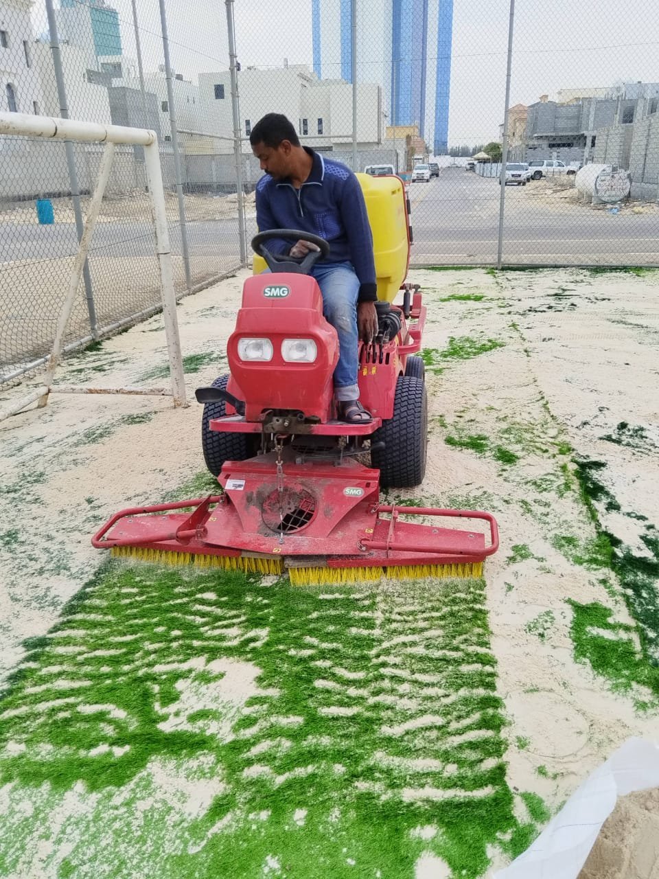 تمشيط العشب الصناعي بالمكينة أثناء التركيب