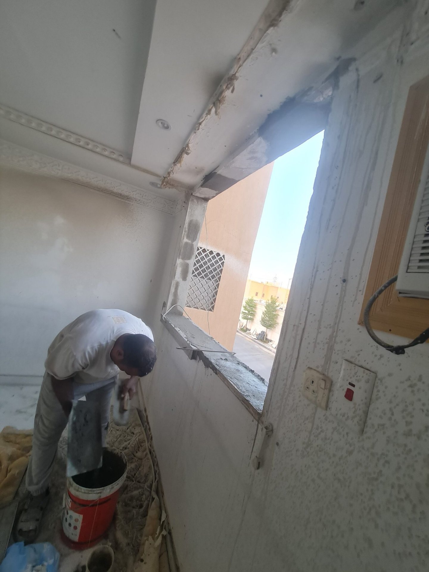 فني يقص فتحة الشباك من الواجهة على السقالة