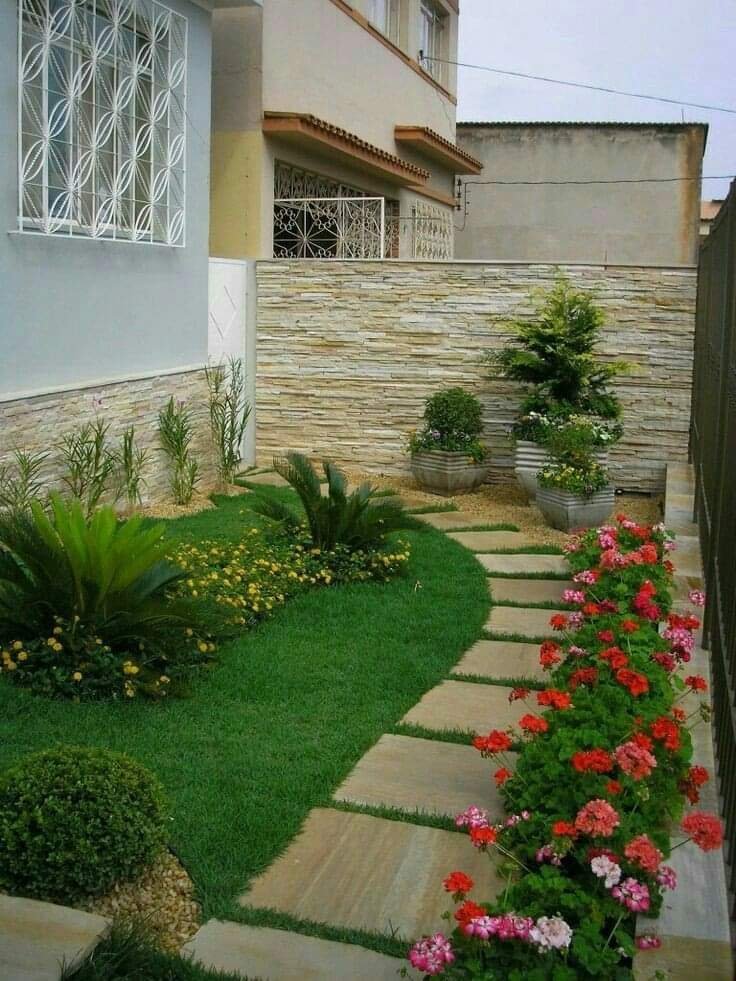 ممر حجري متعرج بين الزهور والجدار الحجري