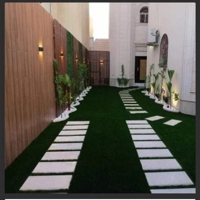 ممر مائل بحوش مع جدارية عشب وإضاءة