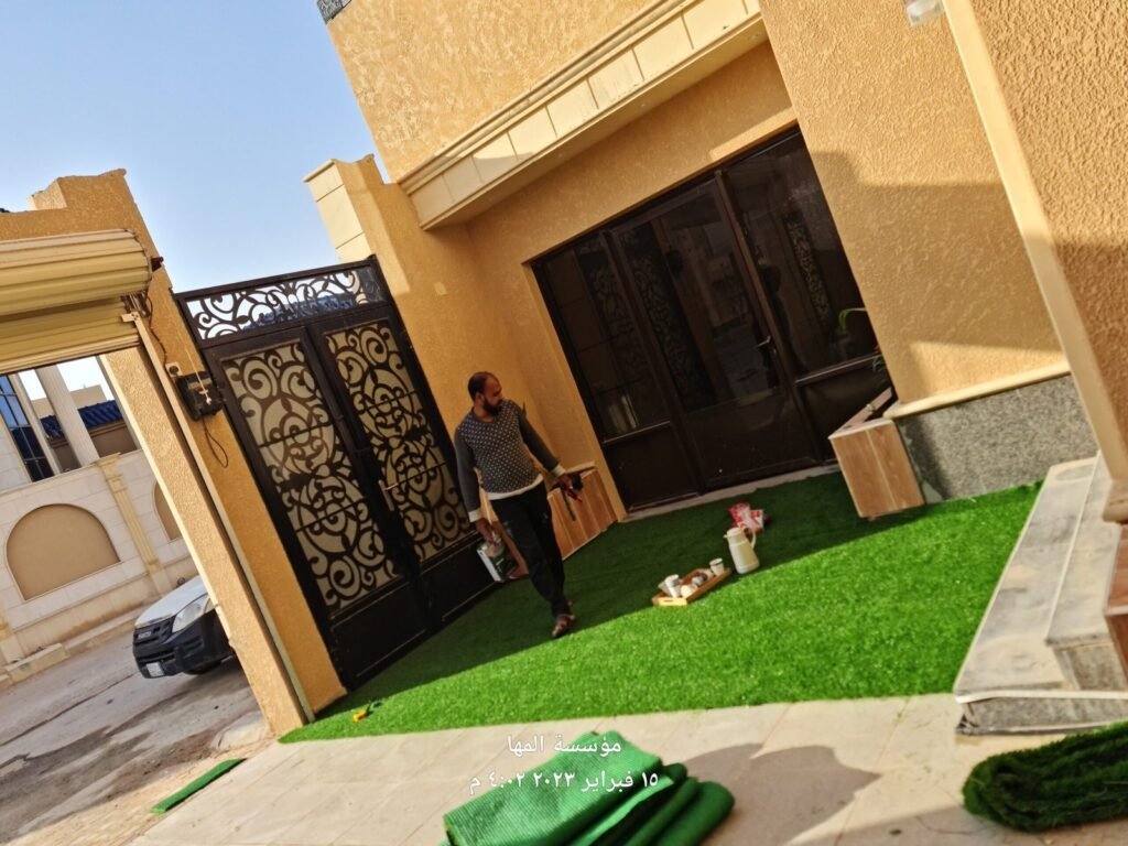 فني أثناء تركيب العشب الصناعي بمدخل فيلا